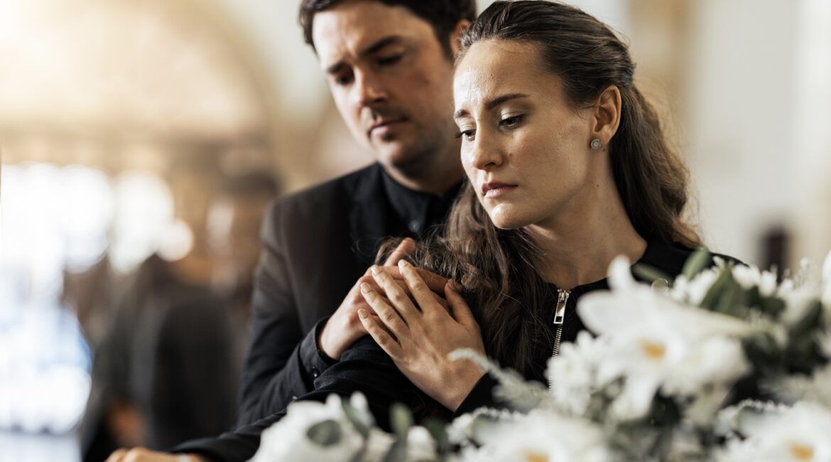 Sad, funeral and flowers with couple and coffin in church for death, respect and mourning. Grief, g